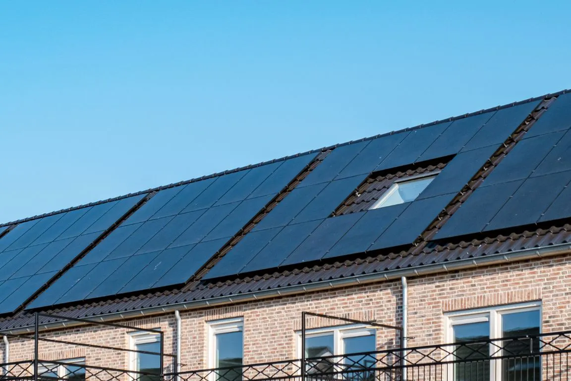 Een dak gevuld met zonnepanelen van Solar Power Systems op aaneengesloten bebouwing.
