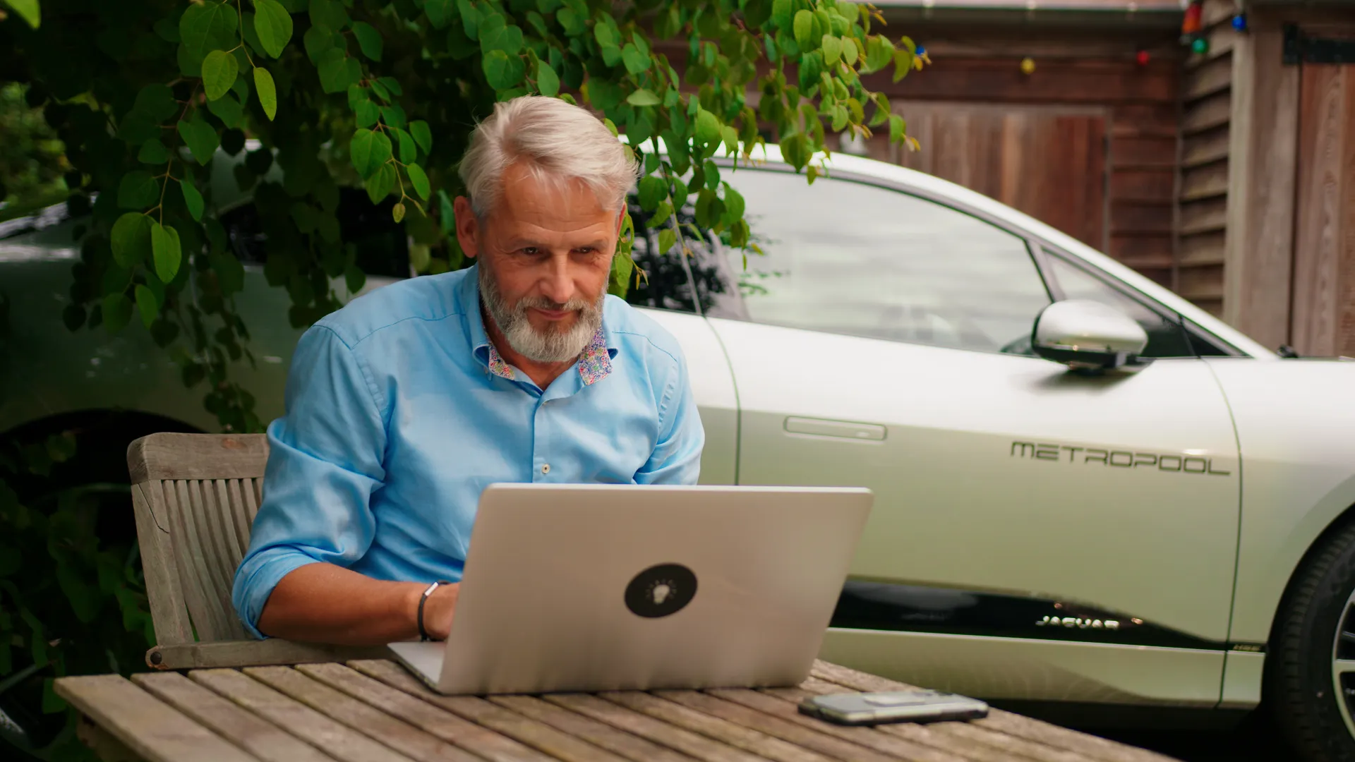 Luc Martens van Solar Power Systems die op een terrasje zit en op een laptop aan het kijken is.